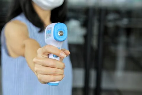 Staff wearing protecting face mask use digital thermal scanner temperature gun Stock Photos