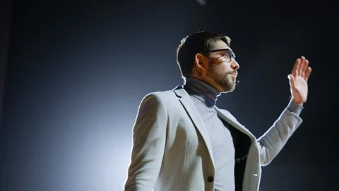 On-Stage Handsome Speaker Greets Audience, Talks about His Ideas, Concepts Stock Footage 122810618
