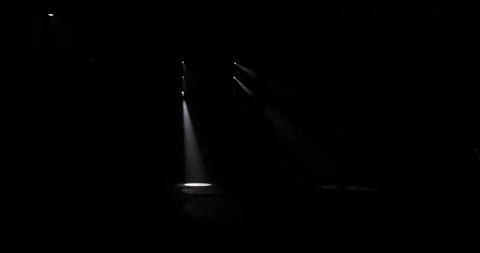 Stage lights flash in a dark setting creating a dramatic spotlight effect Stock Footage 292083981