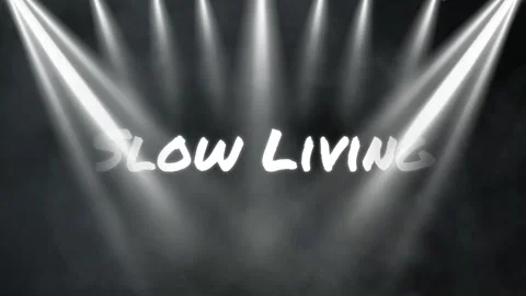 Stage lights illuminating the text slow living against a dark smoky background Stock Footage 338390015