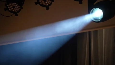 Stage spotlight emitting beam changing from white to blue in smoke Stock Footage 346351193