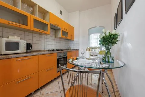 Staged Glass Dining Table in Bright Orange Kitchen Interior 스톡 사진
