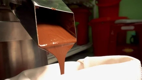 Stages of cocoa mass being put through a juicer to make liquid chocolate. Stock Footage 88954429