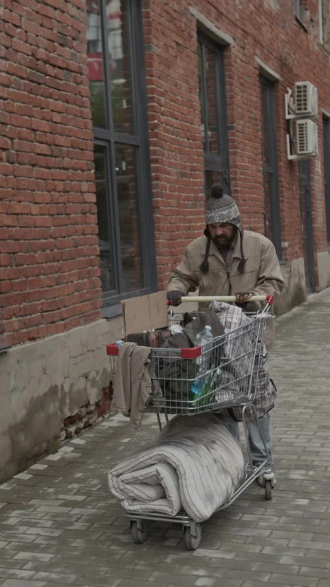 Staggering Middle-Aged Beggar Pushing Shopping Cart with His Belongings Outdoors Stock Footage 317304889