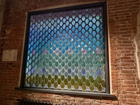 Stained glass window with hexagonal pattern set against red brick wall in w.. Stock Photos
