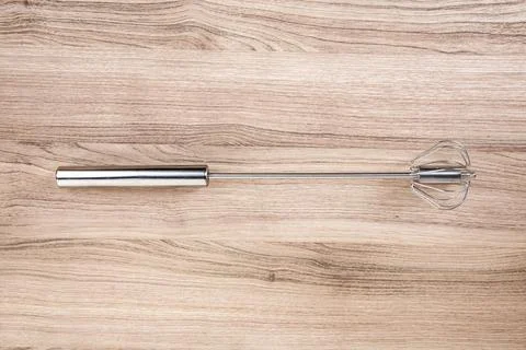 Stainless manual egg beating tool on a wooden cutting board Stock Photos