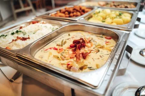 Stainless self-service buffet table with various meals, side dishes and Stock Photos