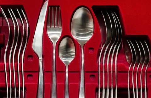 Stainless steel flatware silverware set on red backdrop. Stock Photos