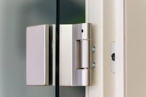 Stainless steel hinge securing modern glass door Stock Photos