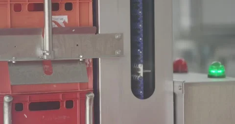 Stainless steel machine moving red stacking crates in a food facility with a Stock Footage 340001962