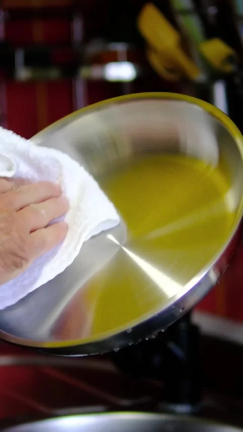 Stainless steel pan wiped with kitchen towel by chef before cooking on clean Stock Footage 345169635