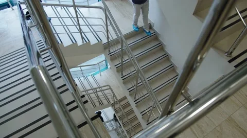 Staircase down in an office building with chrome railings that people descend to Stock Footage 195120466