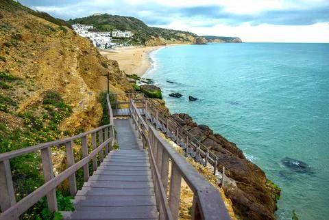 Staircase down rocky cliffs to ocean Salema Beach Portugal Stock Photos