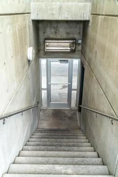 Staircase inside a building going down to a glass door that leads to outdoors Stock Photos