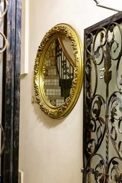 The staircase is reflected in a round mirror next to a wrought iron grate Stock Photos
