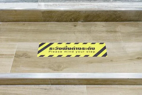 Staircase with warning signage PLEASE MIND YOUR STEP with Thai description Stock Photos