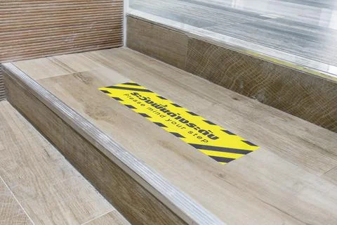 Staircase with warning signage PLEASE MIND YOUR STEP with Thai description Stock Photos