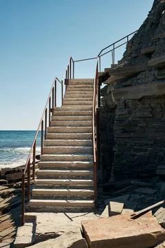 Stairs to the beach surrounded by rocks. Stock-Fotos