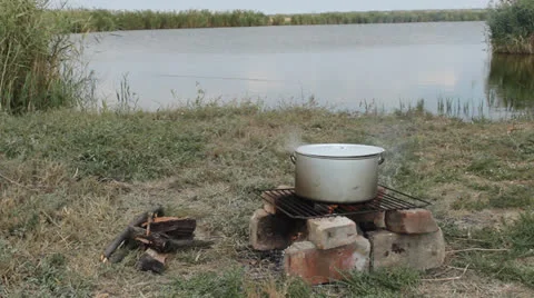 Аt the stake on the bank of the river boiled fish soup Stock Footage 24711209