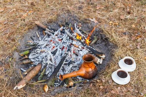 At the stake in the spring forest, a clay Turkish coffee pot is heated agains Stock Photos