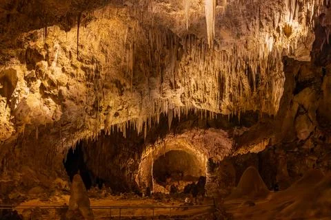 Stalactites drape the ceiling of an illuminated cave. Foto stock