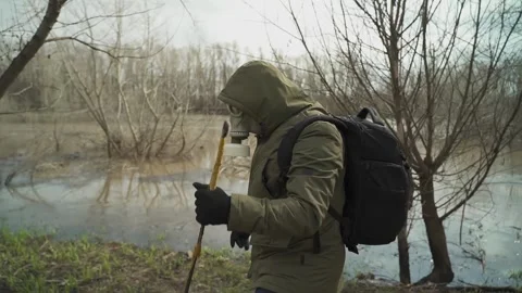 Stalker in a gasmask. Along the river wading through the thickets of the forest Video stock 130523902