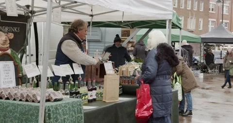 Stall holder takes payment from a customer on mobile phone in Farmers Market Stock Footage 150111368