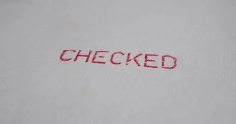 A stamp CHECKED is placed on a sheet of white paper, close-up Stock Footage 251588845