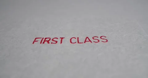 A stamp FIRST CLASS is placed on a sheet of white paper, close-up Stock Footage 251588974