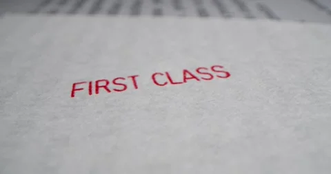 A stamp FIRST CLASS is placed on a sheet of white paper, close-up Stock Footage 251589218