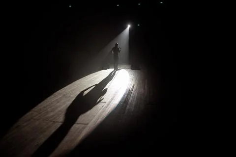Stand up comedian on stage in the beam of light. Stock Photos