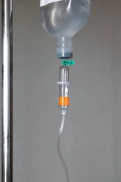A stand with drip bag against wall. Close up saline solution drip for patient. Stock Photos