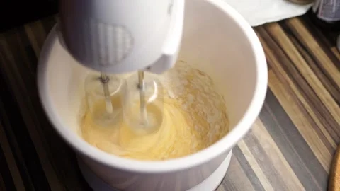 Stand mixer beats raw eggs with flour in a deep bowl on the table Stock Footage 267927000
