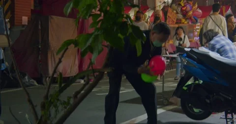 Stand Owner Droping Balloon At Night Market During Chinese New Year Stock Footage 231004805