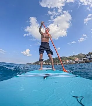 Stand up paddle between rocks and clouds Stock Photos