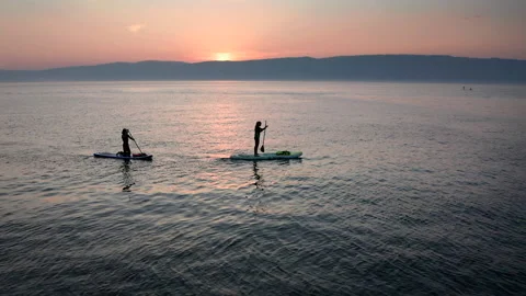 Stand up paddle board silhouette of two women on water, slow motion aerial SUP Stock Footage 202294719