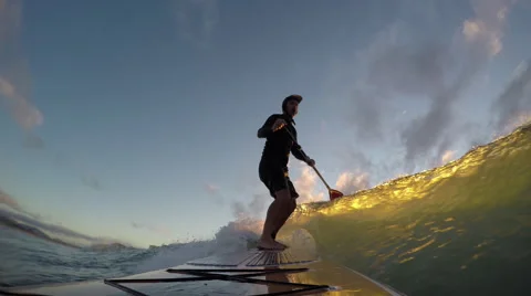 Stand up paddle board surfing a wave at sunset Stock Footage
