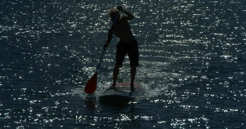 A Stand Up Paddle Boarder or SUP paddling the sea at sunset. Vídeo Stock 86130708