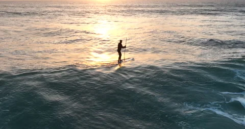 Stand-up paddleboard surfing during sunset in Ericeira, Portugal. Drone shot of Stock Footage 280580050