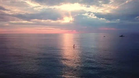 Stand Up Paddleboarder Silhouette Under Dramatic Sunrise Sky with Sun Rays Stock Footage 319804426