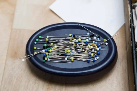 Stand with pins with multi-colored heads on a wooden surface. Stock Photos