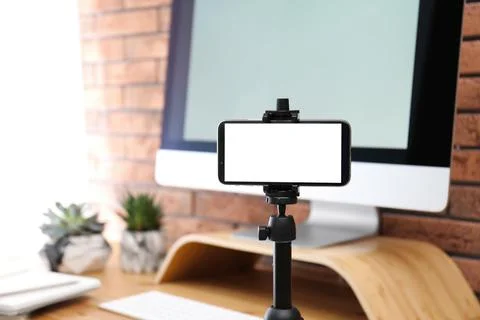 Stand with smartphone near computer on table indoors. Mockup for design Stock Photos