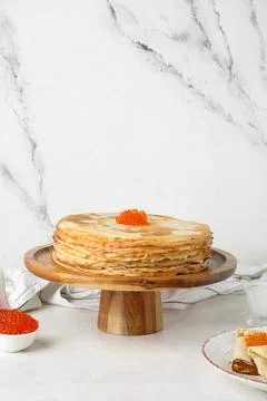 Stand with stack of delicious pancakes and red caviar on white table near mar Fotos de archivo