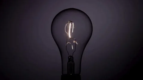 Standard light bulb filament flickers briefly in the dark Stock Footage 329657283