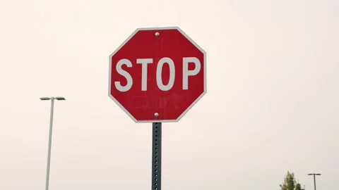 Standard red octagonal stop sign on metal post against overcast sky Stock Footage 342600346