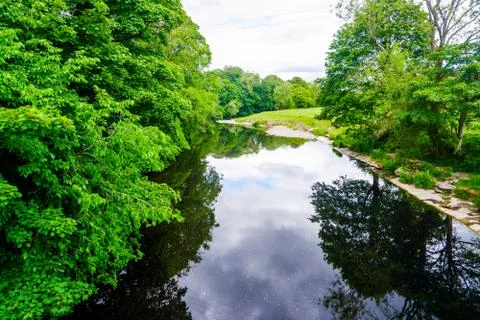 Standing on a bridge looking down a slow moving river with green banks, summe Stock Photos