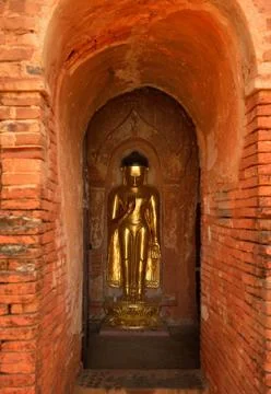 Standing Buddha statue inside one of hundred old small temples in Bagan, Myan Stock Photos
