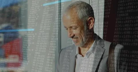 Standing businessman reviewing code overlay on glass in office corridor, with Foto stock