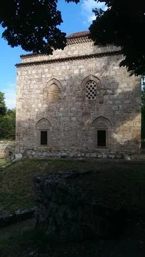 Standing in a clearing between the trees is an old rectangular stone church Stock Photos