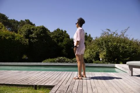Standing on deck by rectangular pool in backyard, African American woman facing Stock Photos